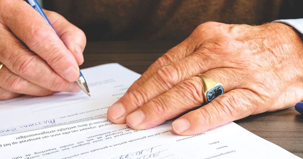Mãos assinando um documento de inventário